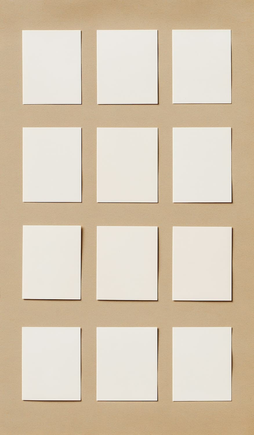 Twelve blank white cards arranged in a neat grid on beige paper